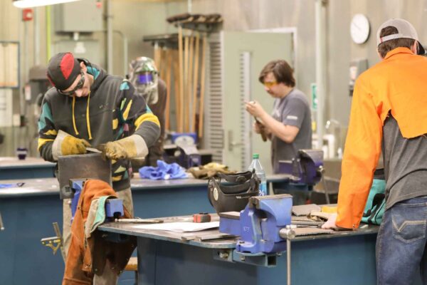 three students working in a welding shop