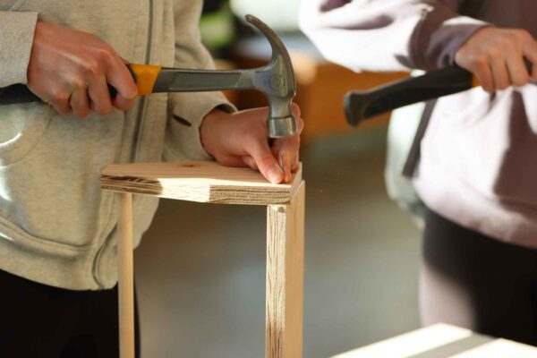 A person is using a hammer to build a wooden toolbox