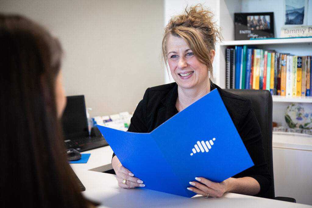 NLC Career advisor smiling at student with folder open between them