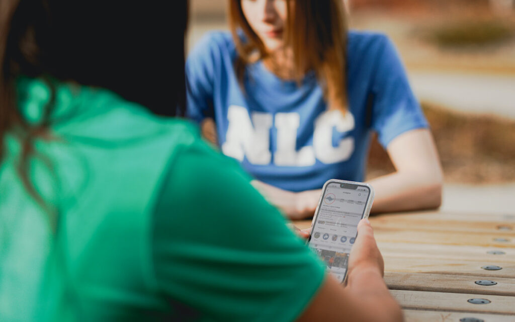 Looking over shoulder of NLC student with phone open to NLC's instagram page