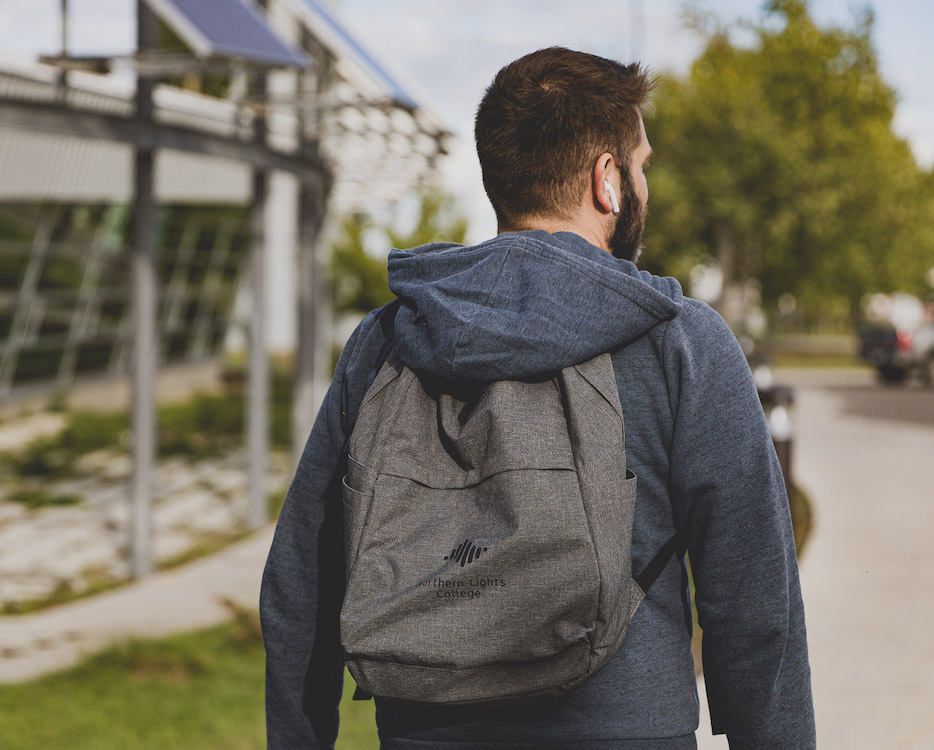 NLC Walking Student on Campus with NLC branded backpack