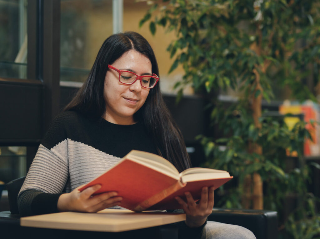 NLC student on campus reading a book