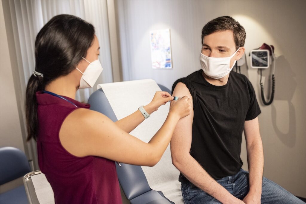 Healthcare professional putting bandaid on patients arm