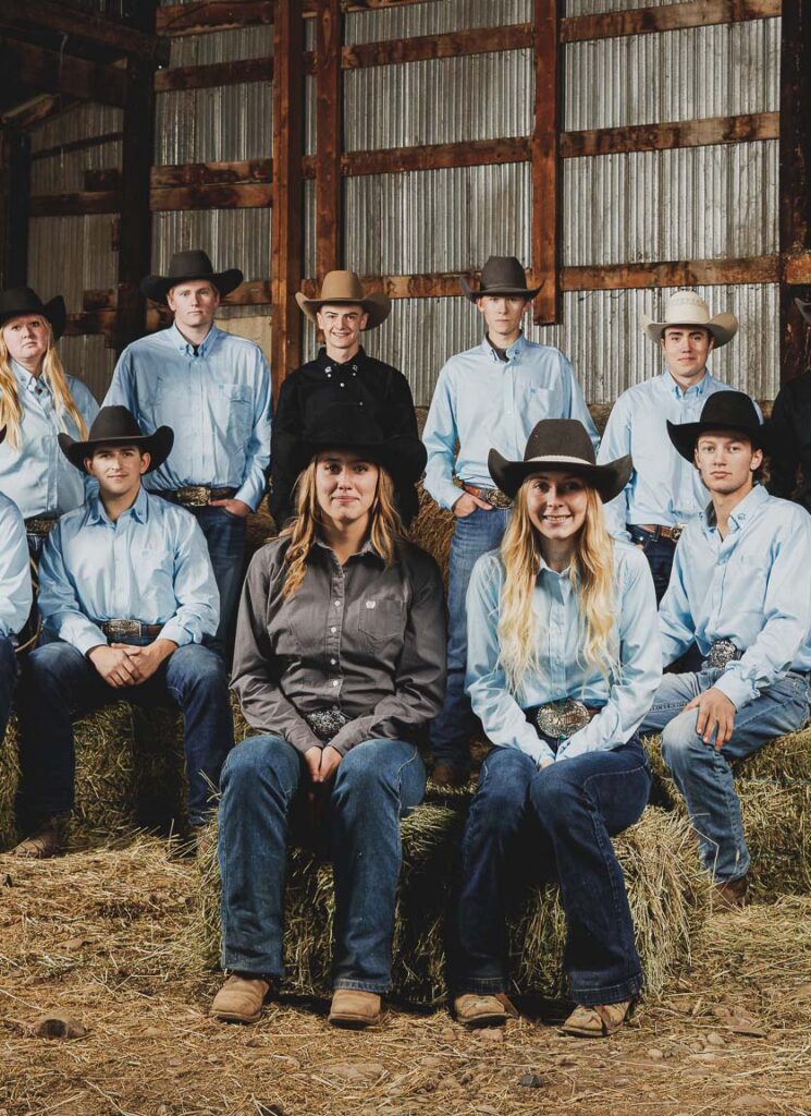 NLC Rodeo team sitting on hay bales and smiling at camera